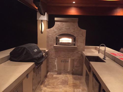 Outdoor kitchen project at night with pizza oven